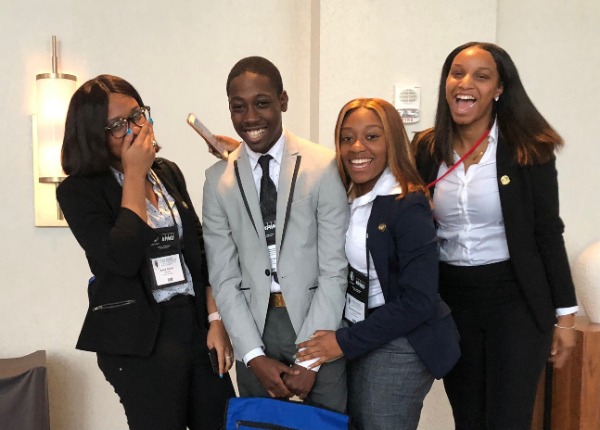 Four students in business attire laughing