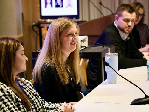 Young adults seated at a table with microphones
