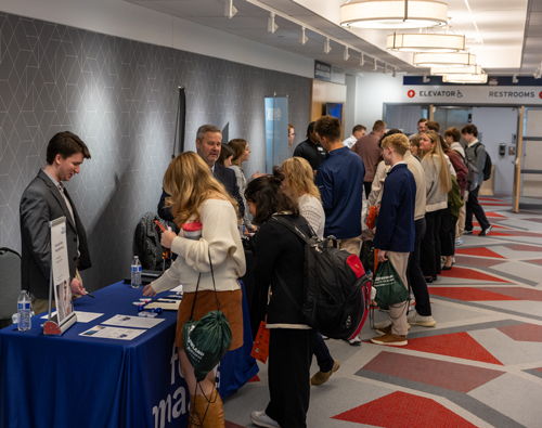 A hallway of students meeting with exhibitors