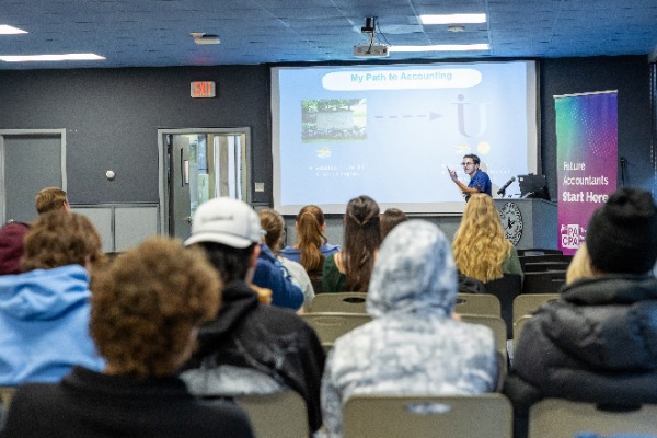 Speaker at whiteboard speaking in front of a classroom of students