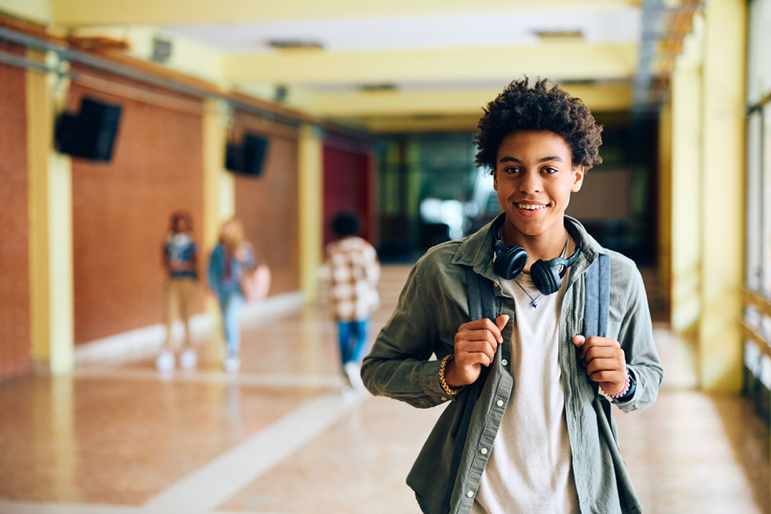Smiling high school student standing in hallway