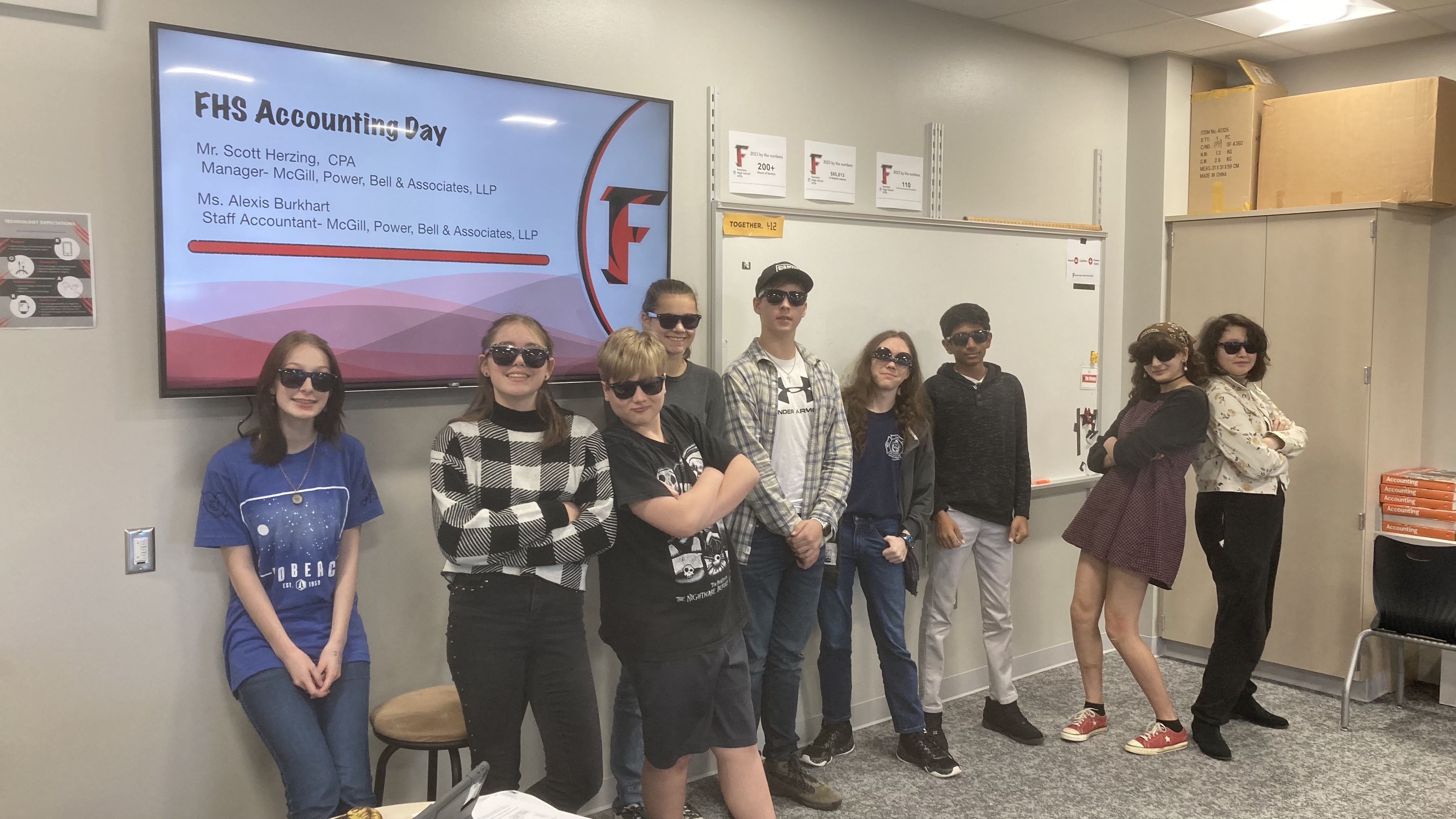 group of students wearing sunglasses posing in front of classroom whiteboard