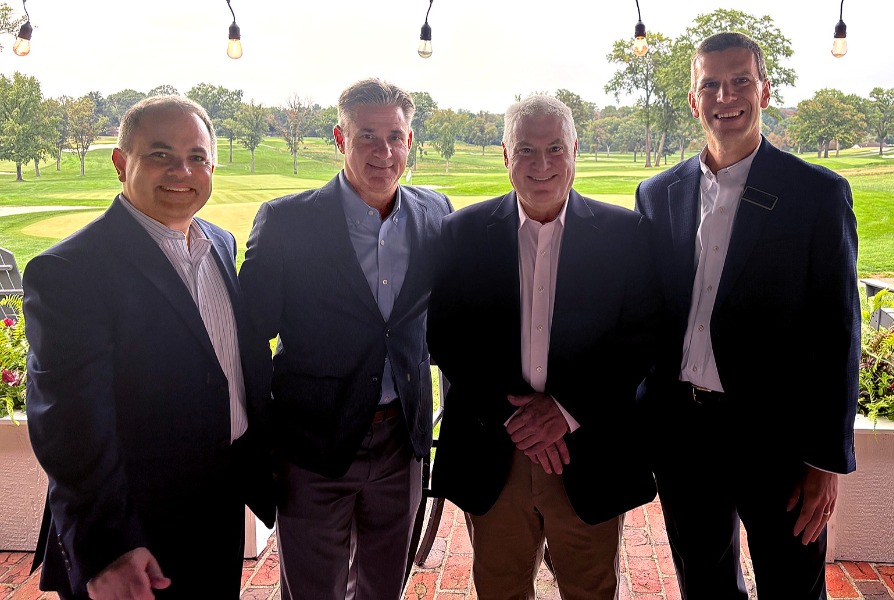 Four men in suits standing on a golf course