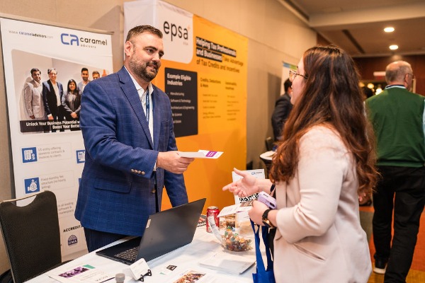 Exhibitor handing papers to a conference attendee