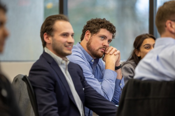 Three IMPACT Summit, two male, and one female, listening intently and smiling