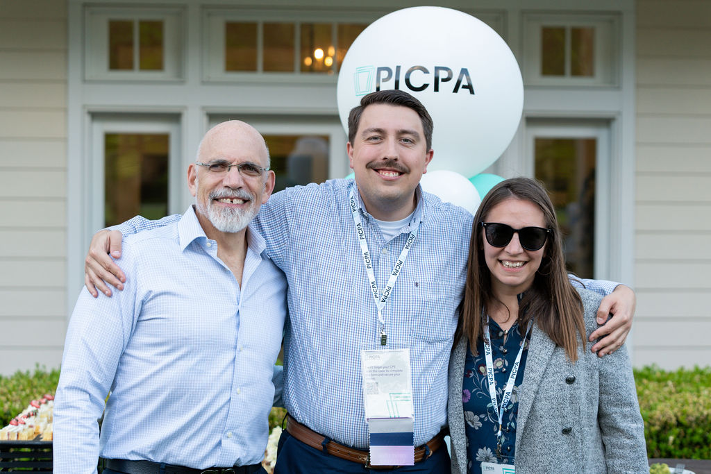 Three Annual Meeting attendees posing outside with arms around one another
