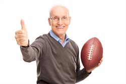 Older man with football giving thumbs-up