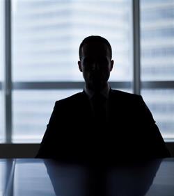 Man in shadow at a boardroom table