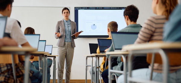 Teacher showing a financial presentation while standing in front of a classroom of students