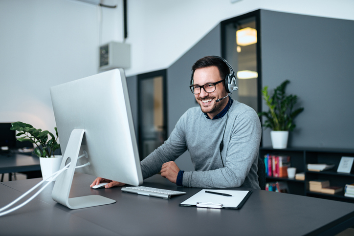 smiling man with headset on sitting at computer