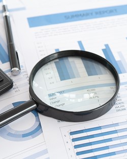 Magnifying glass over charts and data