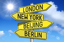 Sign post pointing in different directions toward: London, New York, Beijing, and Berlin