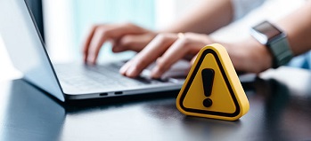 Working on a computer with a yellow warning triangle on the desk