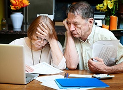 Elder couple looking discouraged while reviewing finances