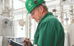 Man in an industrial setting checking his tablet